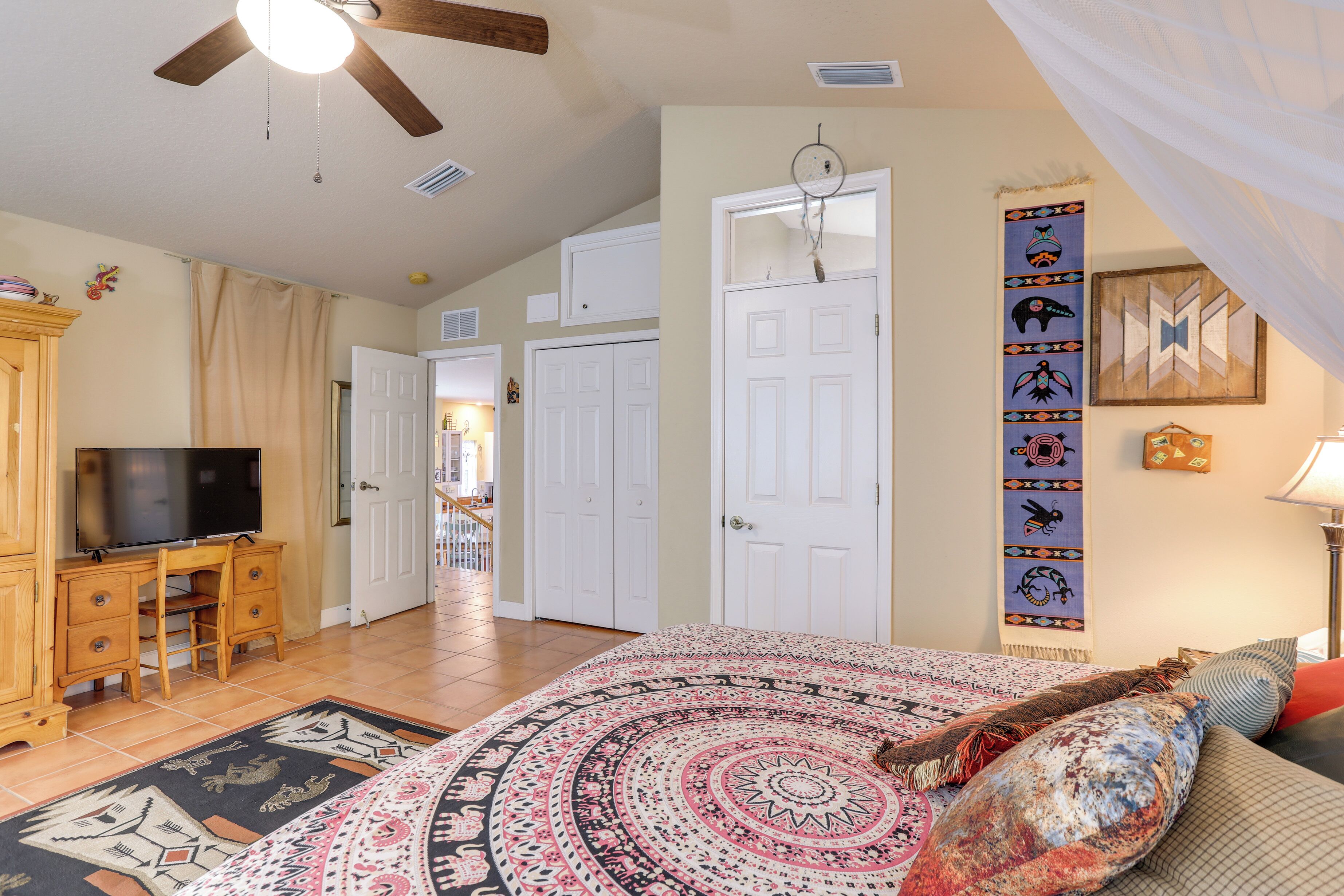 A bedroom with a bed, a desk, a television, and a door.