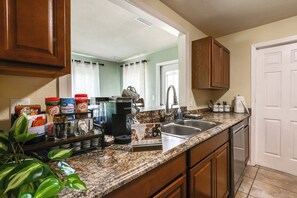 A kitchen with a coffee station, cabinets, a sink, and a door. - Mcgarity Lakehouse: Disney & Universal Day Trip (Deltona)