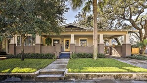 A two-story house with a front porch, a small front yard, and a staircase leading to the entrance.