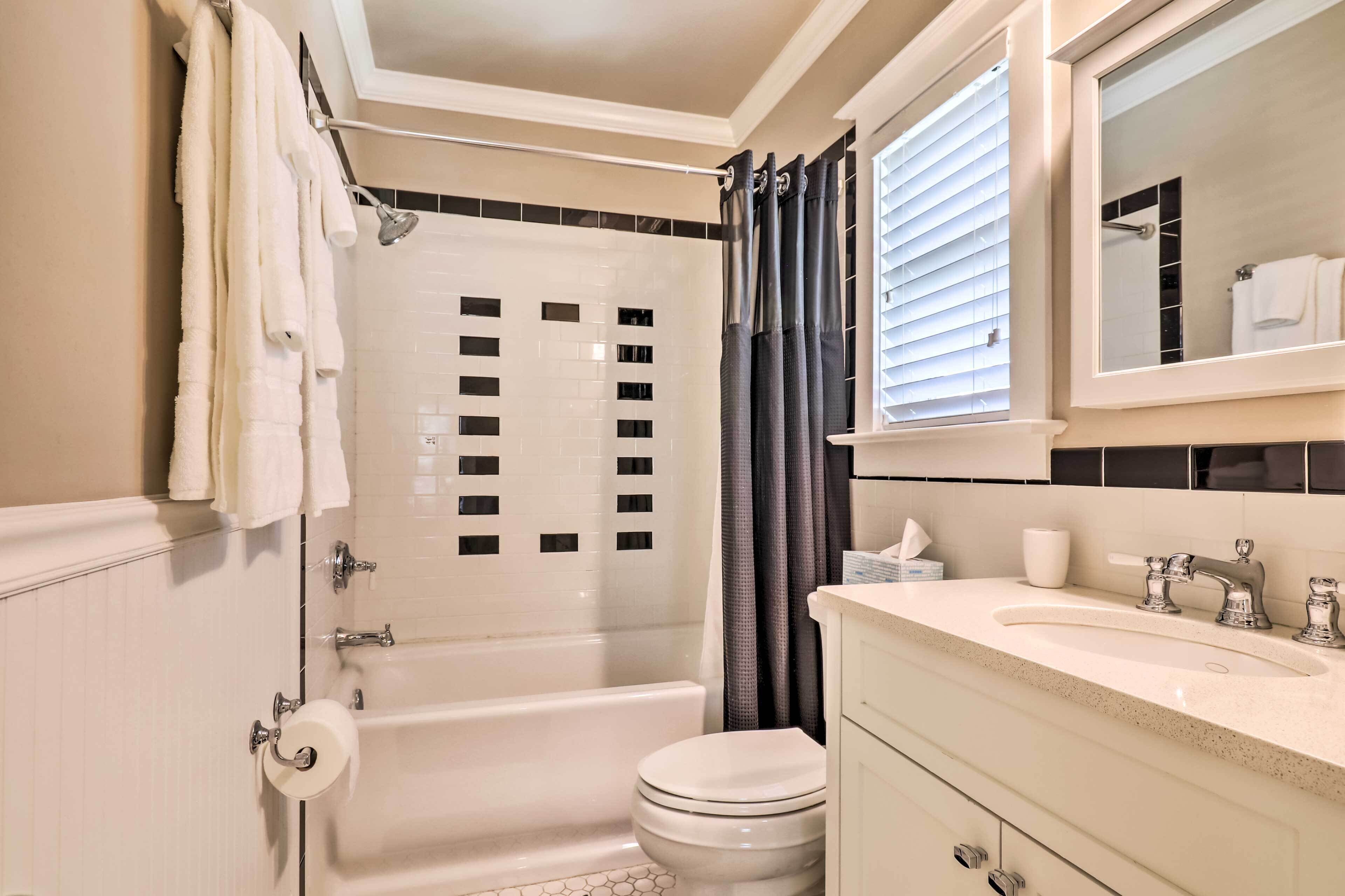 Un baño con bañera, inodoro, lavabo y un espejo sobre el lavabo.