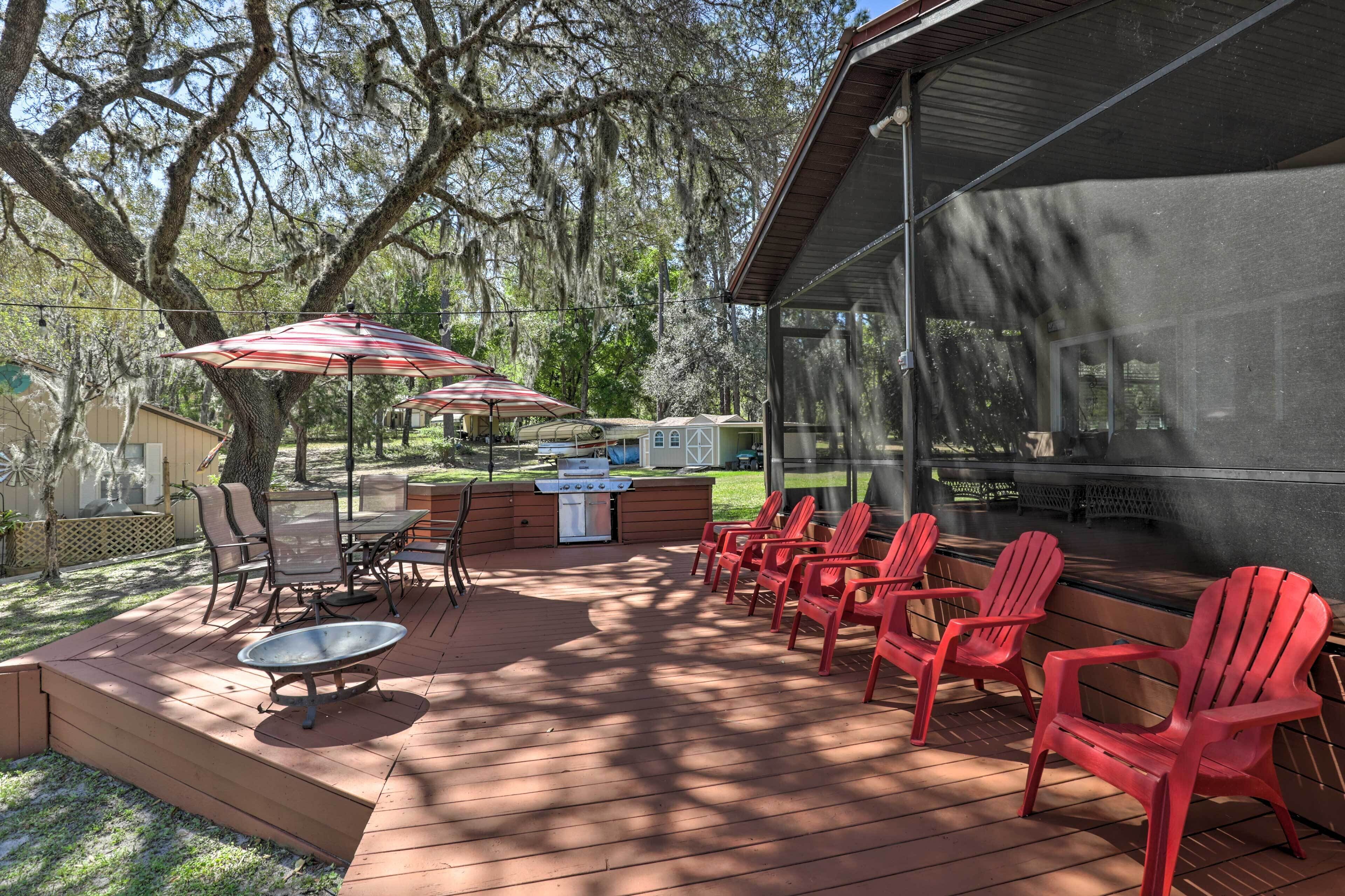 Une terrasse extérieure équipée d’un barbecue, de chaises et de parasols.