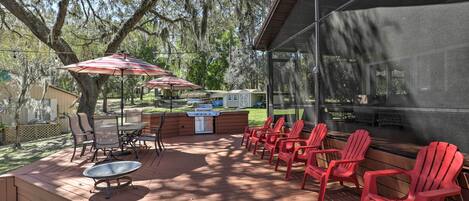 Une terrasse extérieure équipée d’un barbecue, de chaises et de parasols.