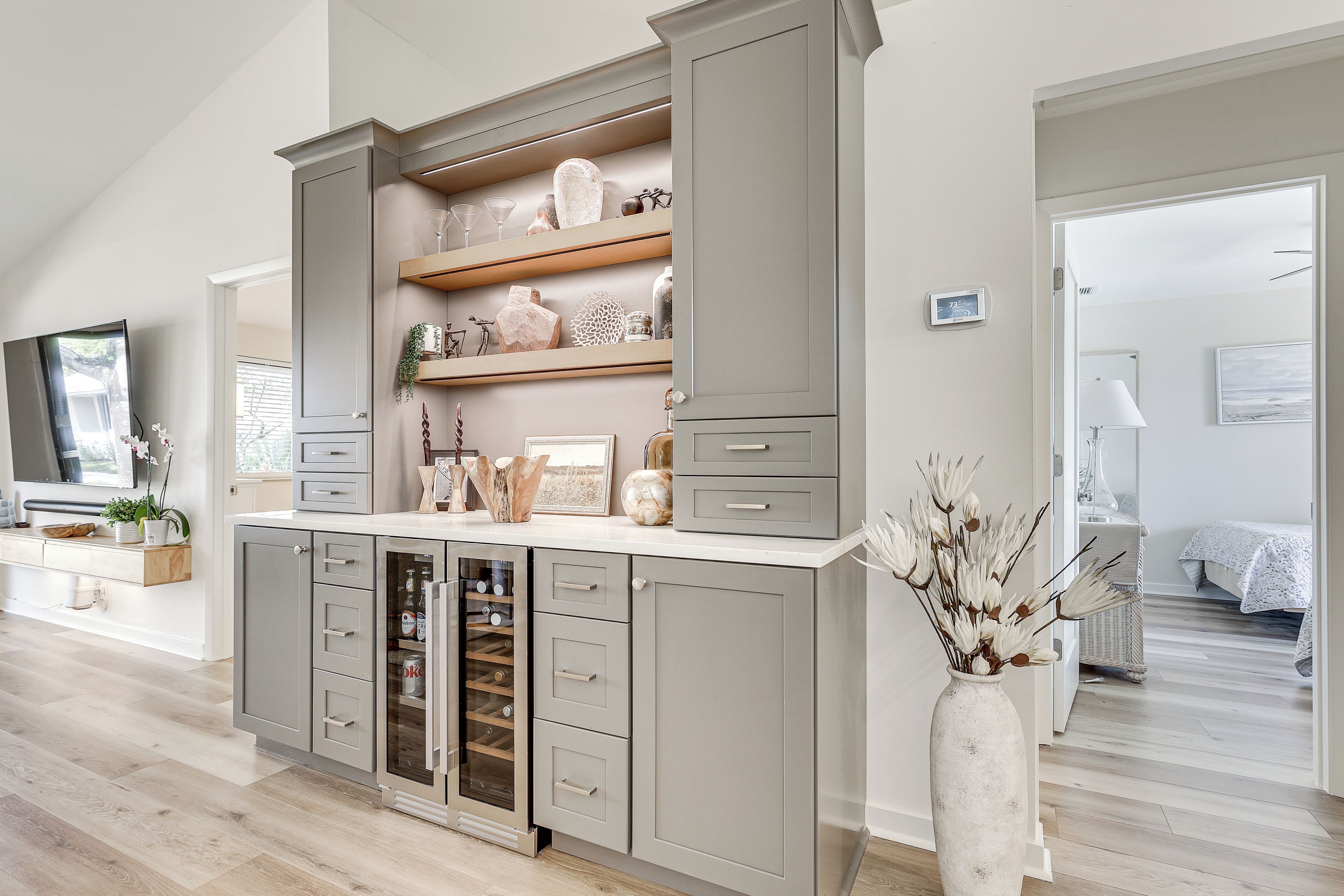 A modern kitchen with grey cabinetry, open shelving, and a wine cooler.