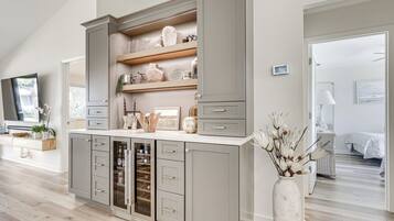 A modern kitchen with grey cabinetry, open shelving, and a wine cooler.