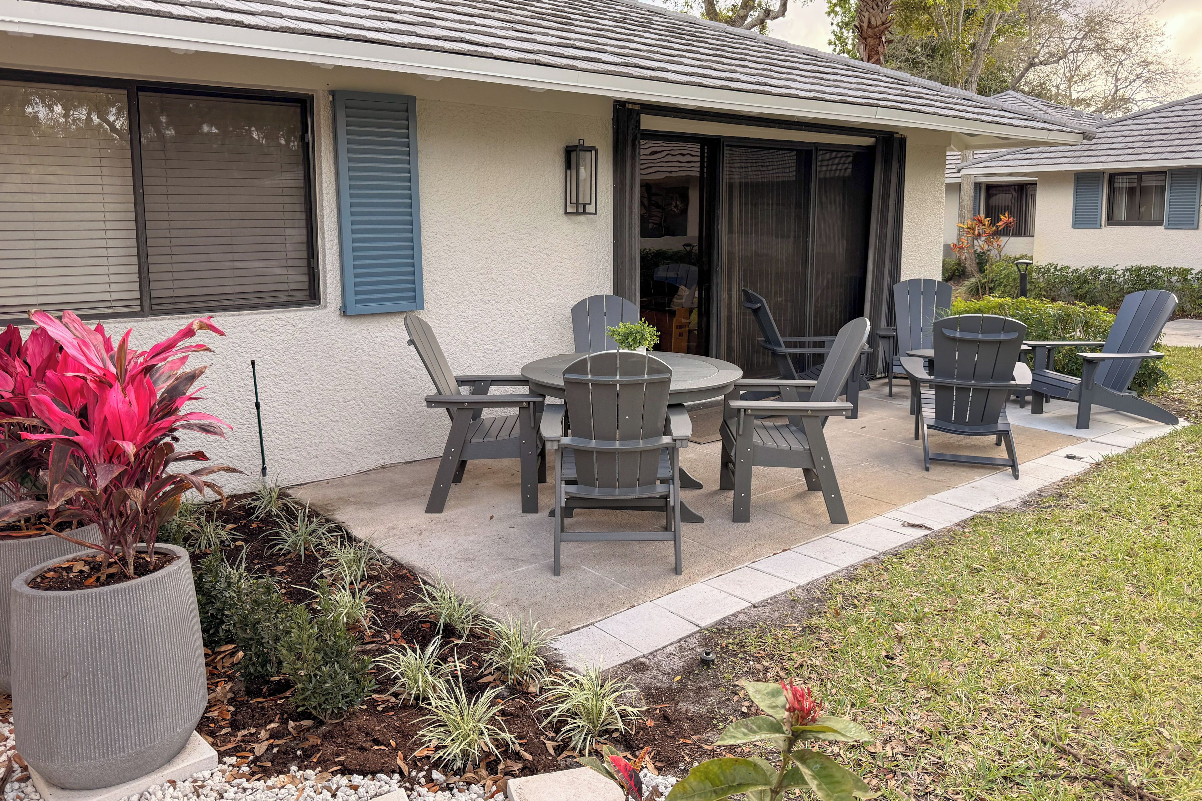 A patio with a table and chairs, a potted plant, and a small garden area.