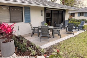 A patio with a table and chairs, a potted plant, and a small garden area.
