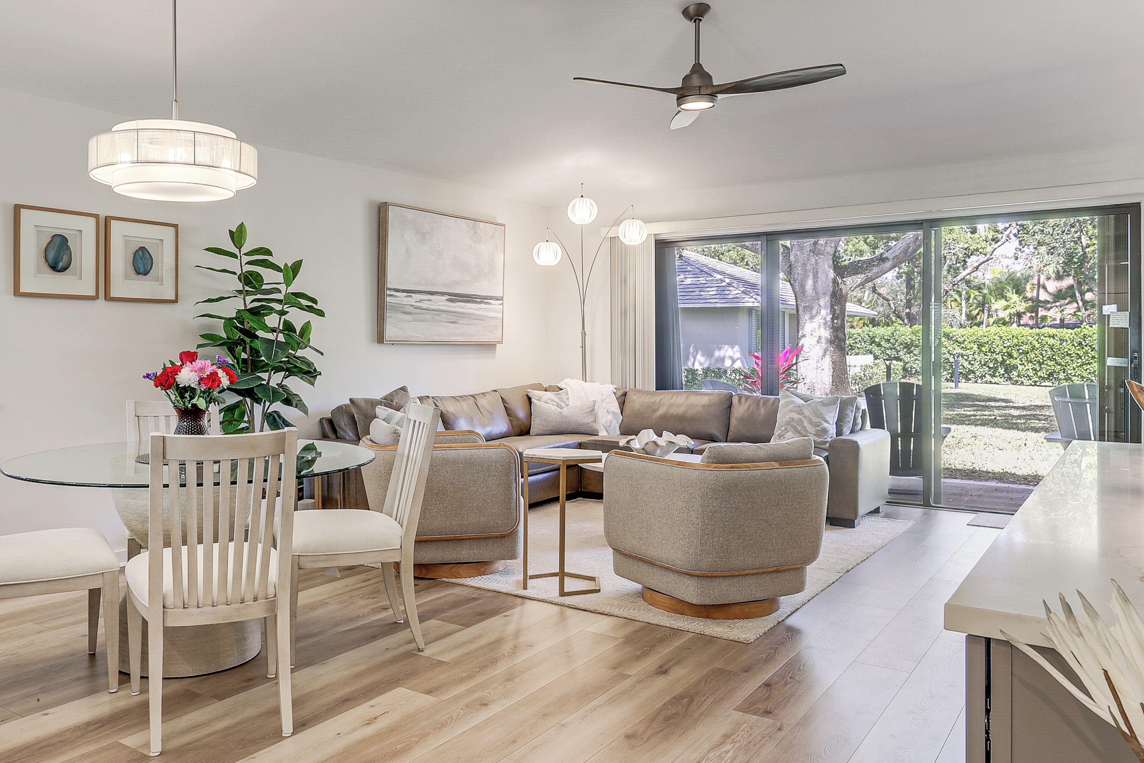 Un salon moderne avec une table à manger en verre, deux canapés et un ventilateur de plafond.