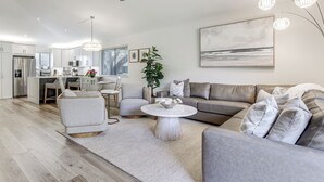 Un salon moderne avec un canapé gris, une table basse ronde et un coin repas comprenant une table et des chaises blanches.