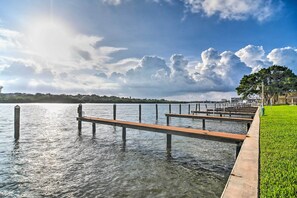 Un muelle de madera se adentra en aguas tranquilas, rodeado de césped y árboles.