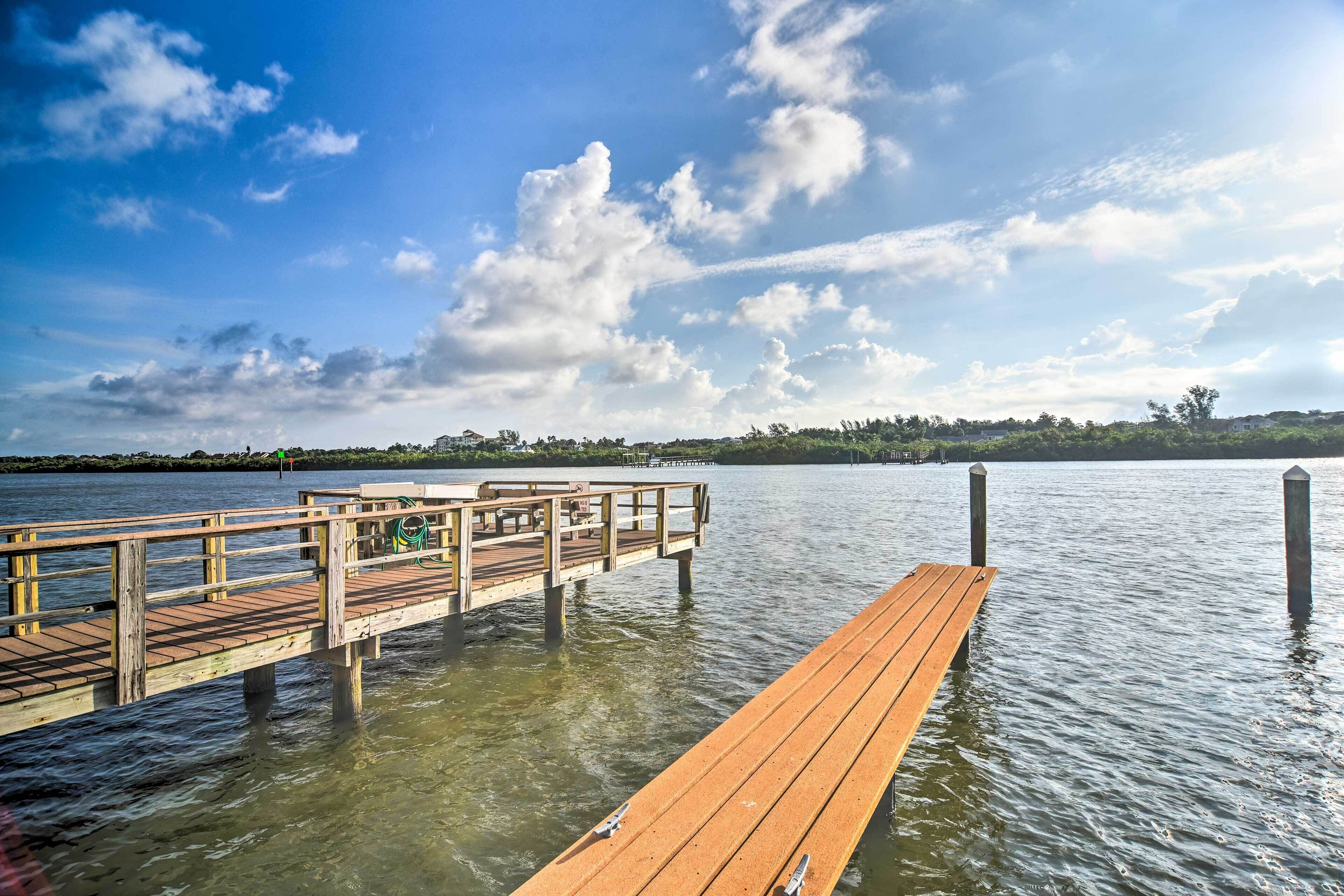 A wooden pier extending into a calm body of water with a clear sky above.