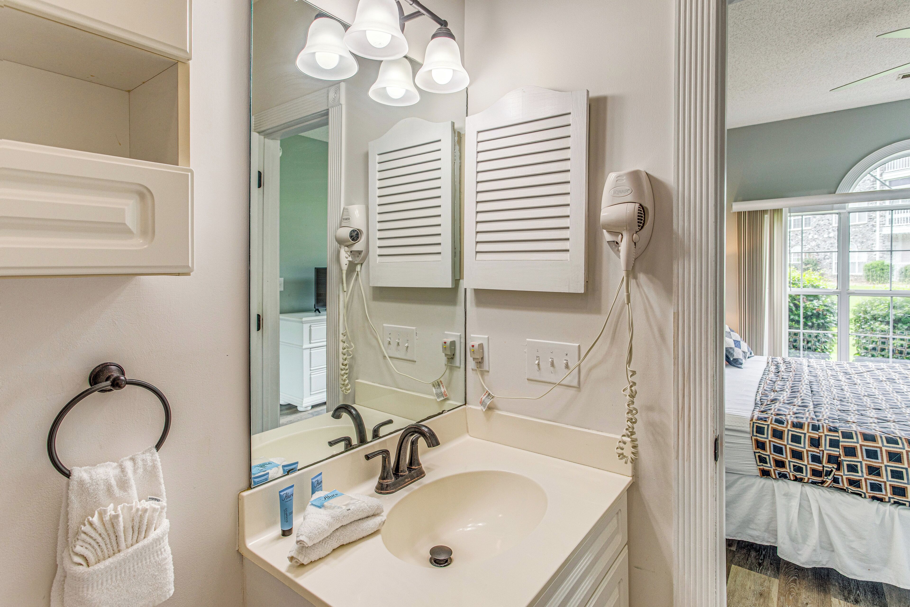 A bathroom with a sink, mirror, towel rack, and hairdryer.