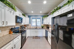 Una cocina con armarios blancos, un refrigerador de acero inoxidable, un microondas y un lavaplatos.