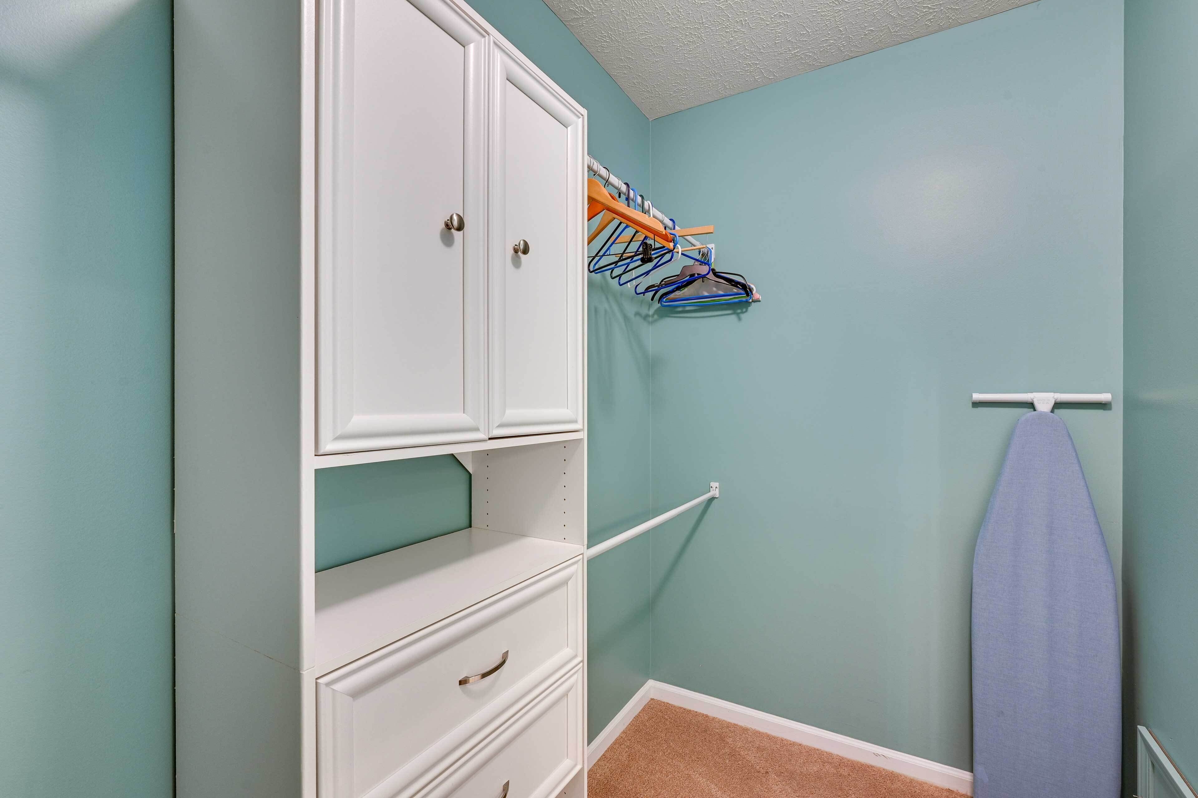 A closet with white cabinetry, a hanging rack, and a hanging garment.