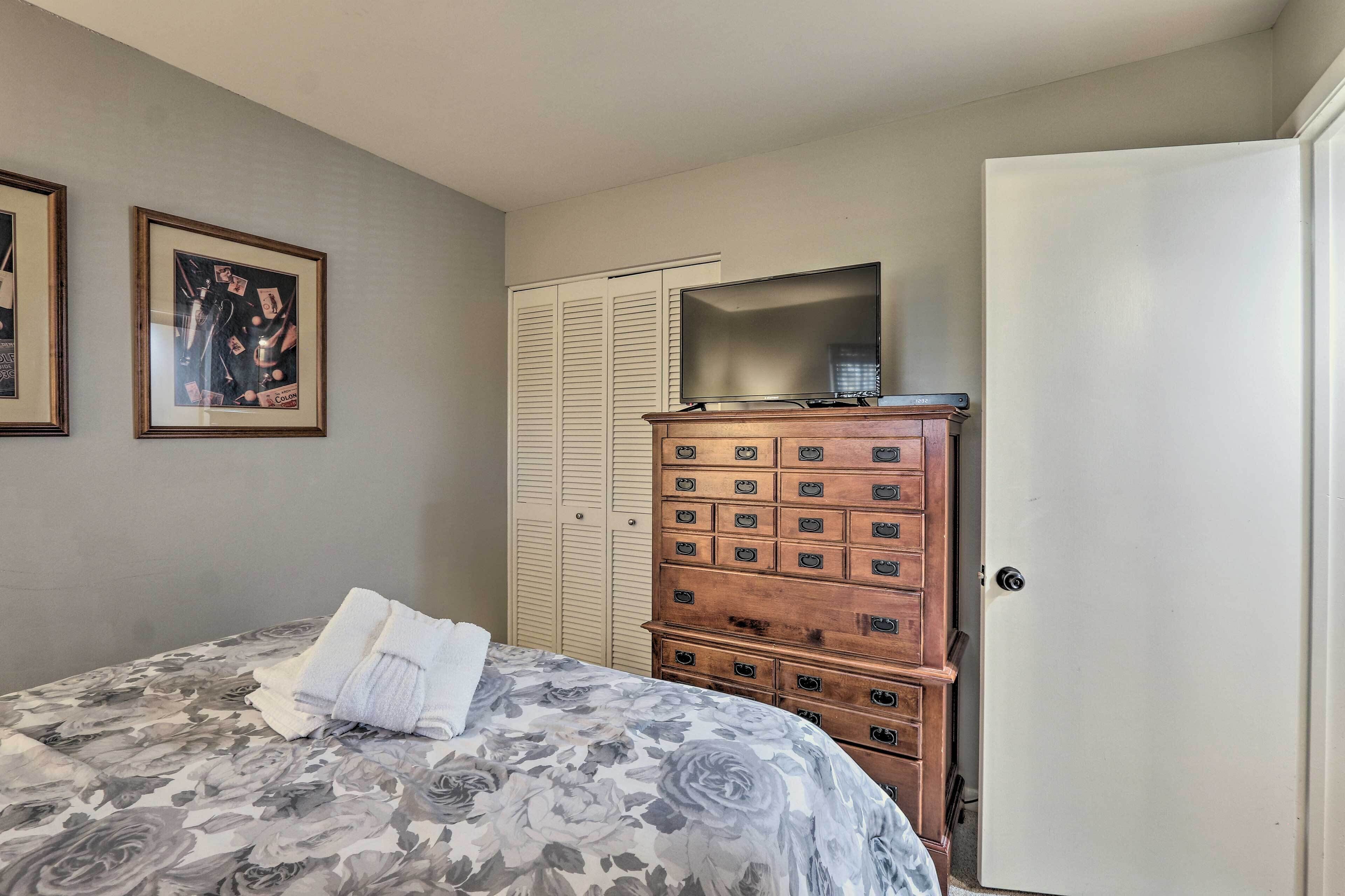 A bedroom with a bed, a dresser, a wardrobe, and a television.