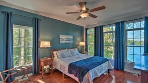 A bedroom with a bed, two bedside tables, a ceiling fan, and large windows with curtains. - Lake Keowee Escape w/ Dock, Deck & Lake Access! (Six Mile)
