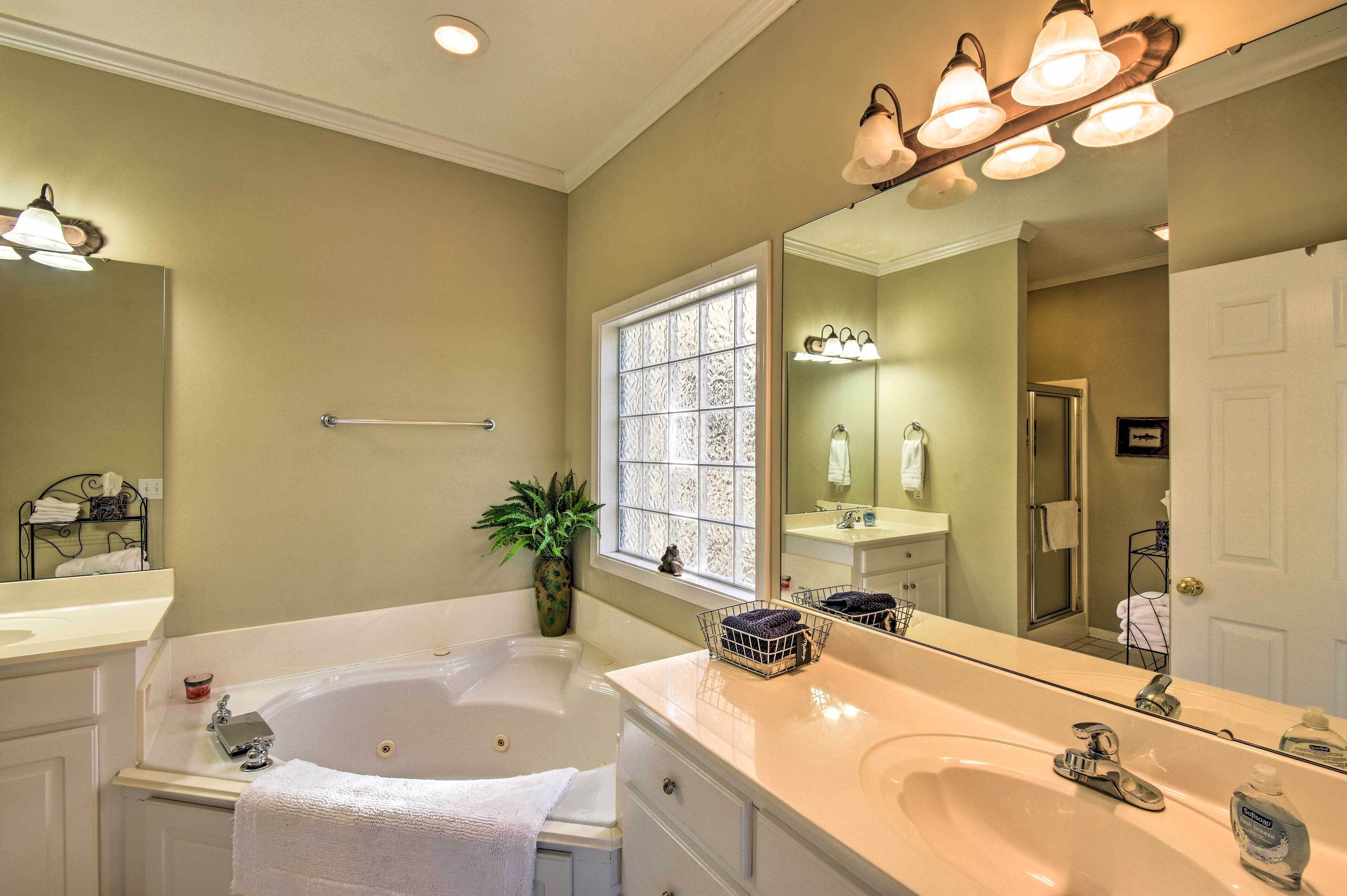 A bathroom with a large bathtub, a double sink vanity, and a large mirror.