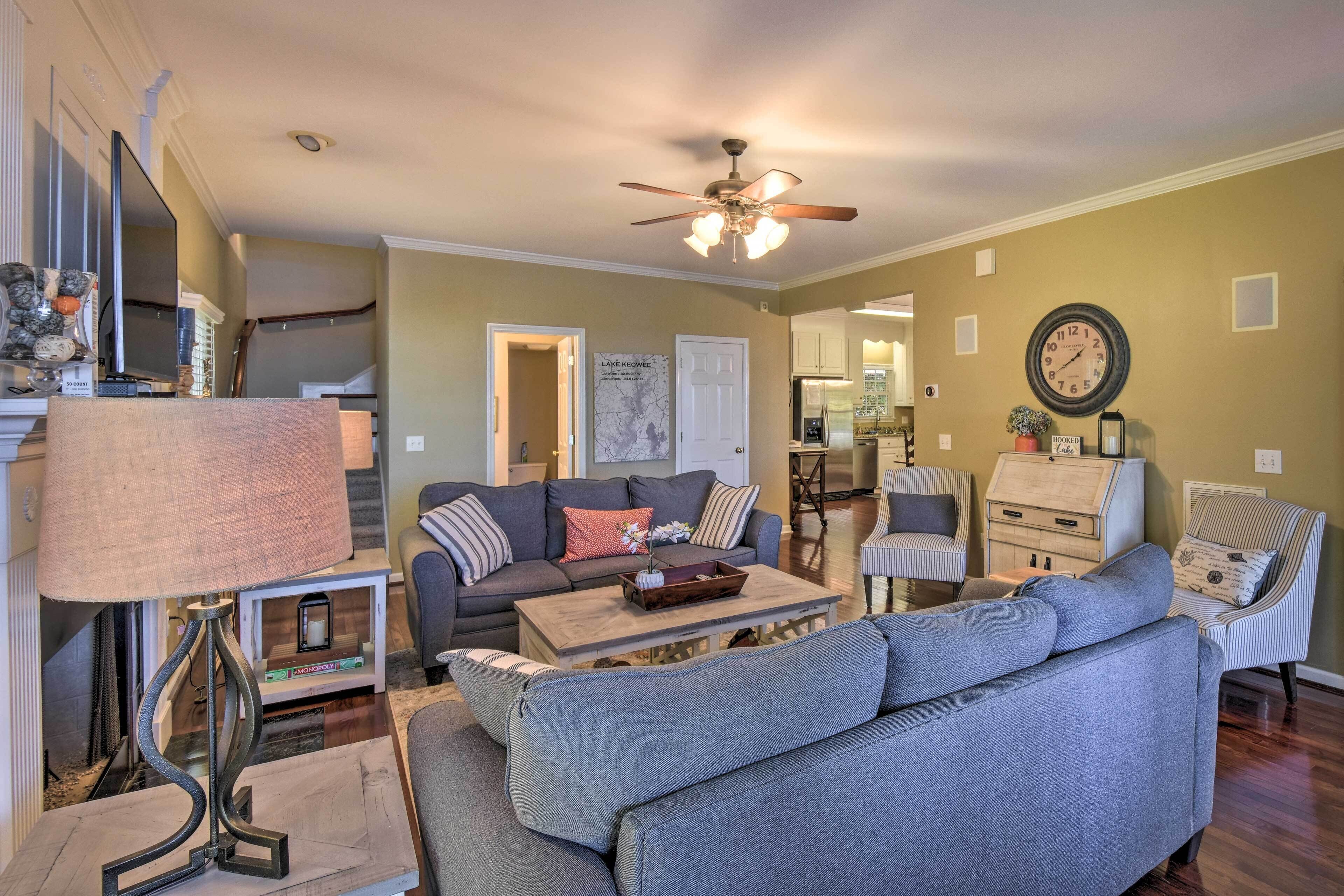 A living room with a sofa, coffee table, and a lamp. There is a ceiling fan and a clock on the wall.
