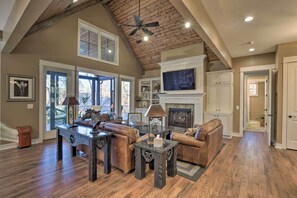 A spacious living room with a fireplace, leather sofas, and a television. - Lake Keowee Cottage w/ Deck & Private Dock! (Seneca)