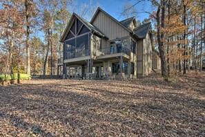 A large, modern two-story house with a balcony and large windows, surrounded by trees and a leaf-covered ground. - Lake Keowee Cottage w/ Deck & Private Dock! (Seneca)