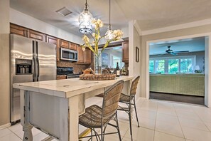 A kitchen with a large island, stainless steel appliances, wicker chairs, and a view to the dining area. - Huge Lutz Family Retreat w/ Game Room & Pool! (Lutz)