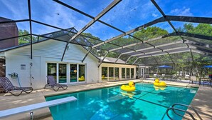 An indoor pool area with clear glass walls, lounge chairs, and a poolside umbrella. - Huge Lutz Family Retreat w/ Game Room & Pool! (Lutz)