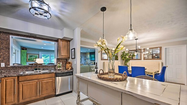 A modern kitchen with wooden cabinets, a stainless steel dishwasher, and a central island with blue chairs. - Huge Lutz Family Retreat w/ Game Room & Pool! (Lutz)