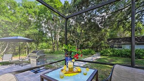 An outdoor patio with a grill, seating, and a table with drinks and a pitcher. - Huge Lutz Family Retreat w/ Game Room & Pool! (Lutz)