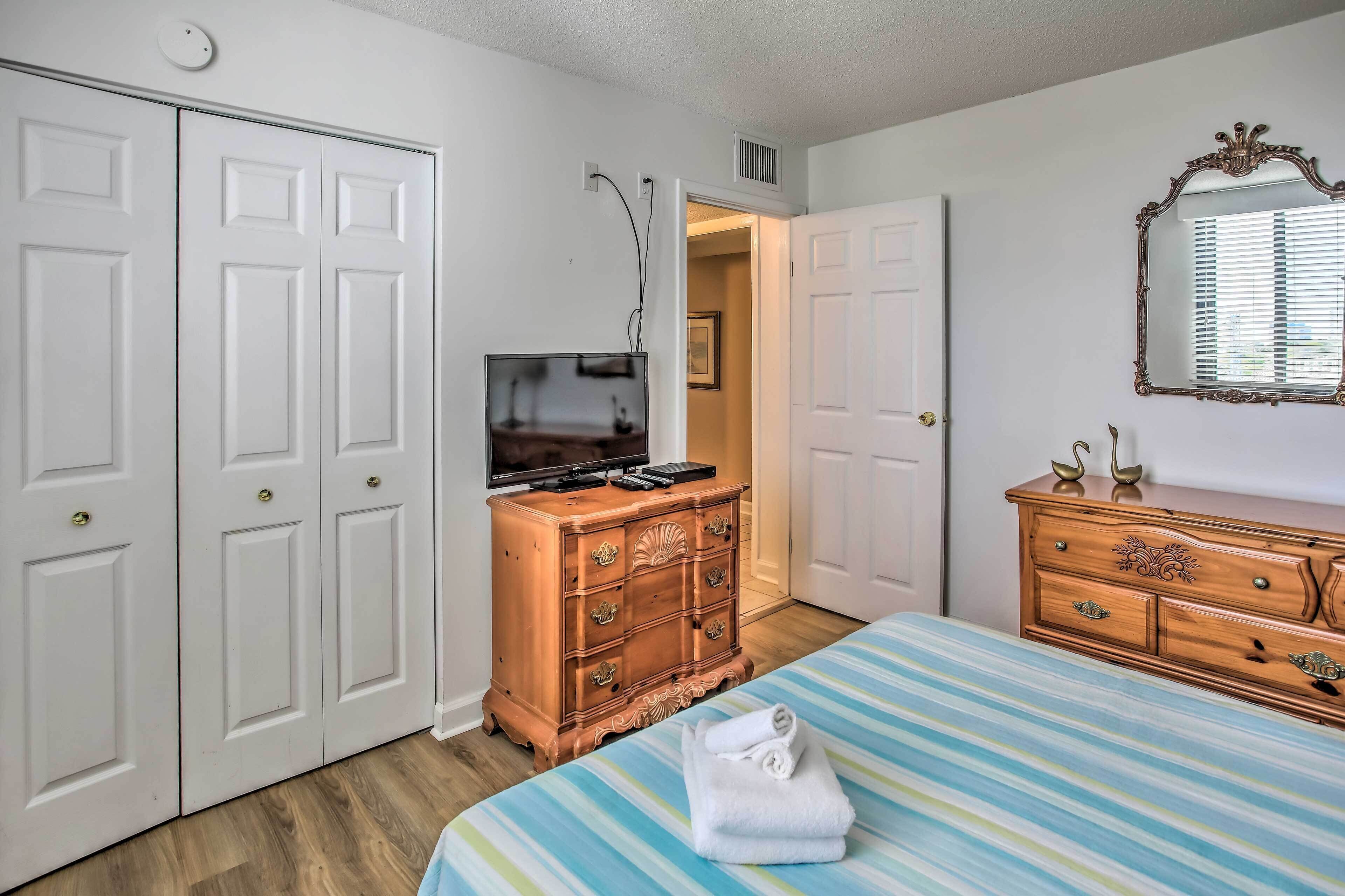 A bedroom with a bed, a dresser, a television, and a wardrobe.