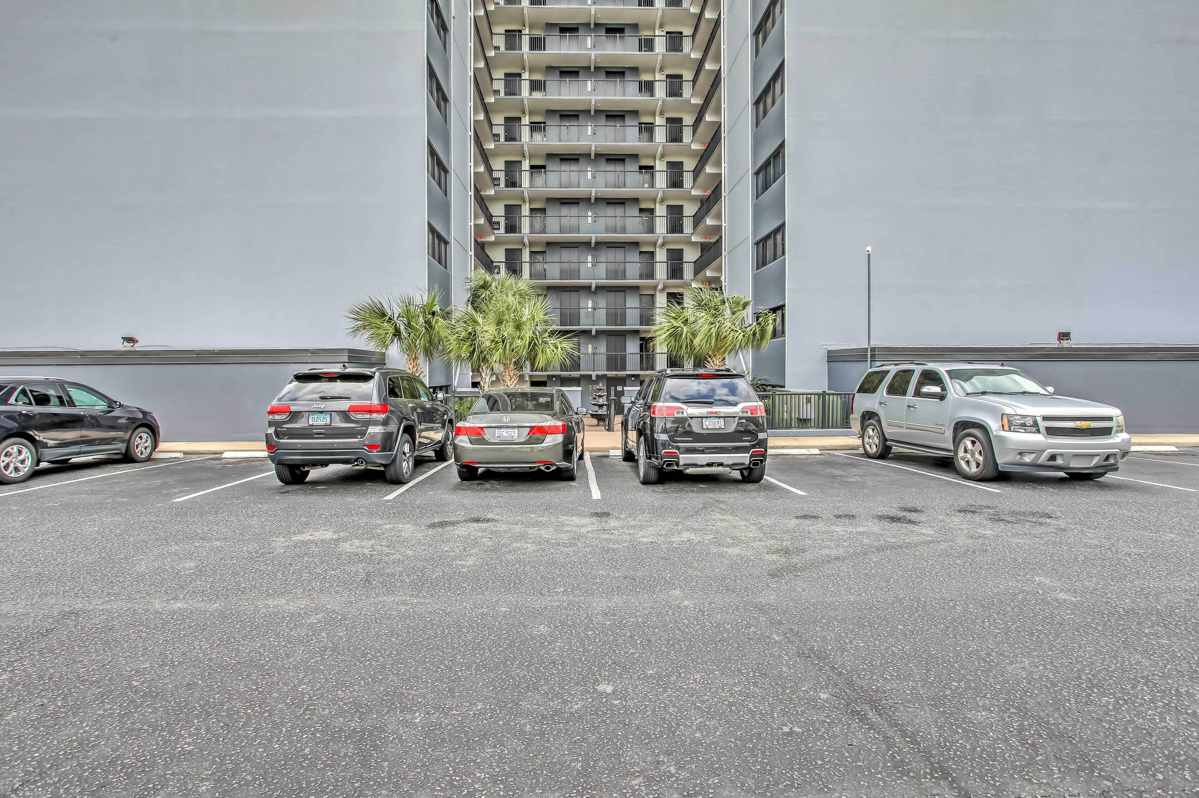 Ein Parkplatz mit mehreren parkenden Autos vor einem hohen Gebäude mit zahlreichen Balkonen.