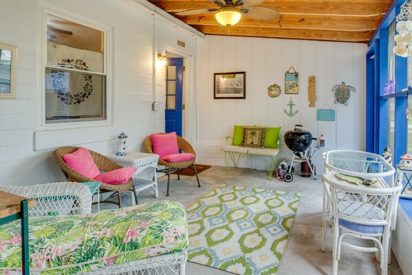 A cozy room with wicker furniture, a patterned rug, and a blue door.