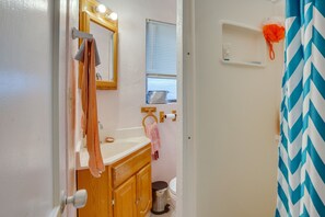 A bathroom with a wooden vanity, a mirror, a sink, a toilet, and a shower curtain.