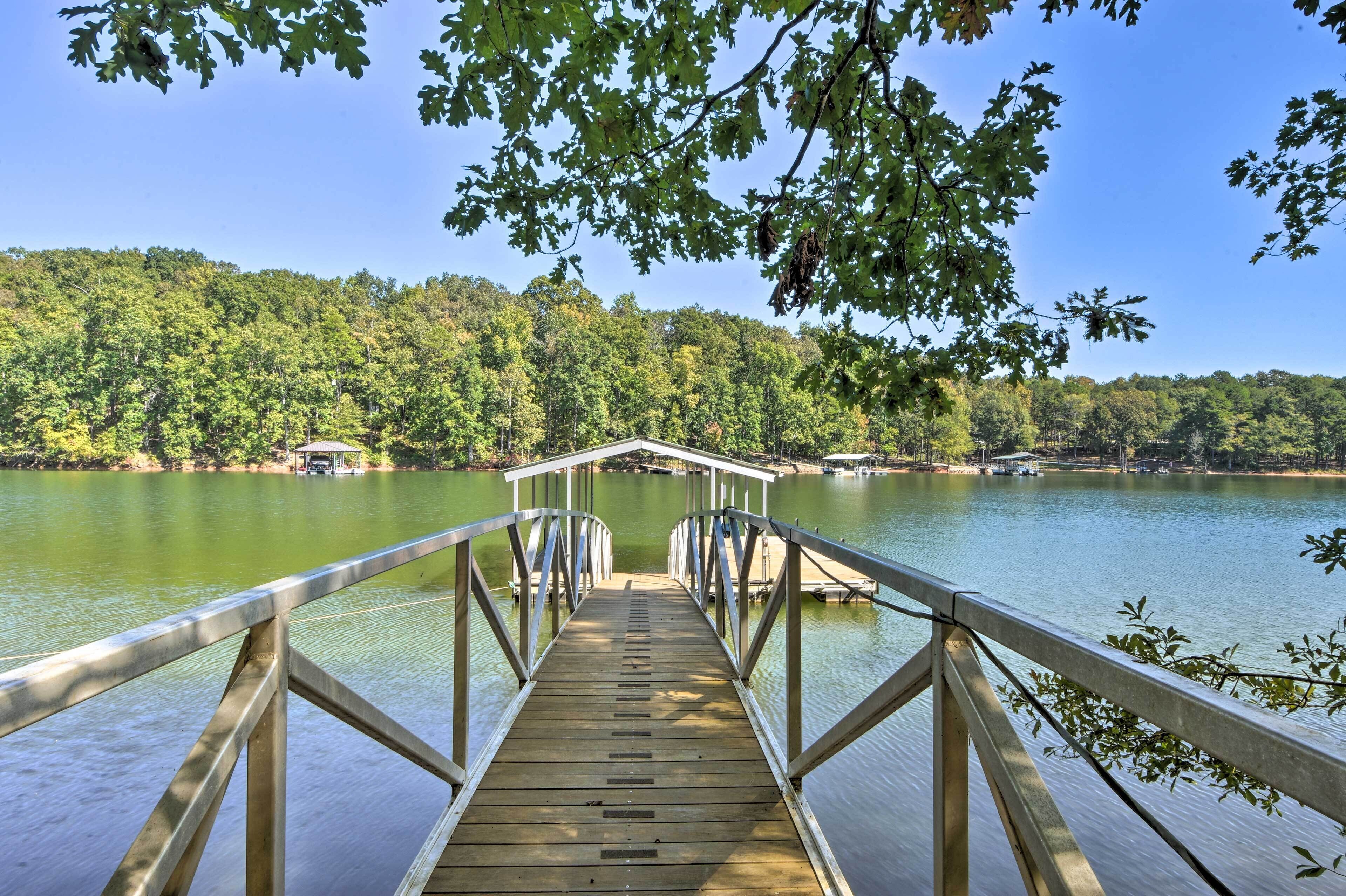 A wooden dock leading to a calm lake surrounded by dense forest.