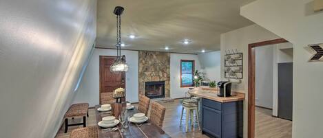 A dining area with a long wooden table, wicker chairs, and a hanging light fixture.
