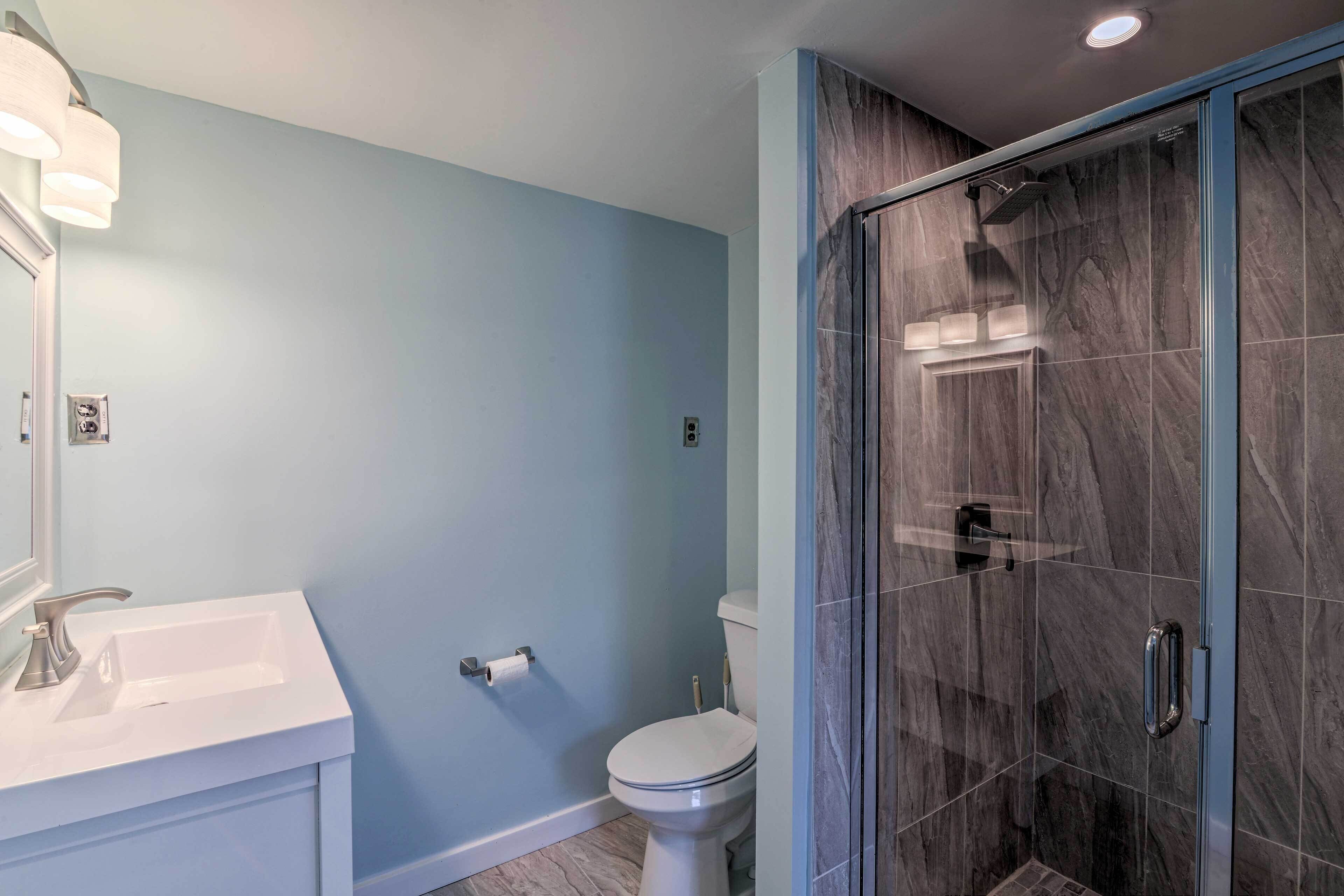 Un bagno con un lavandino bianco, un water e un box doccia in vetro.
