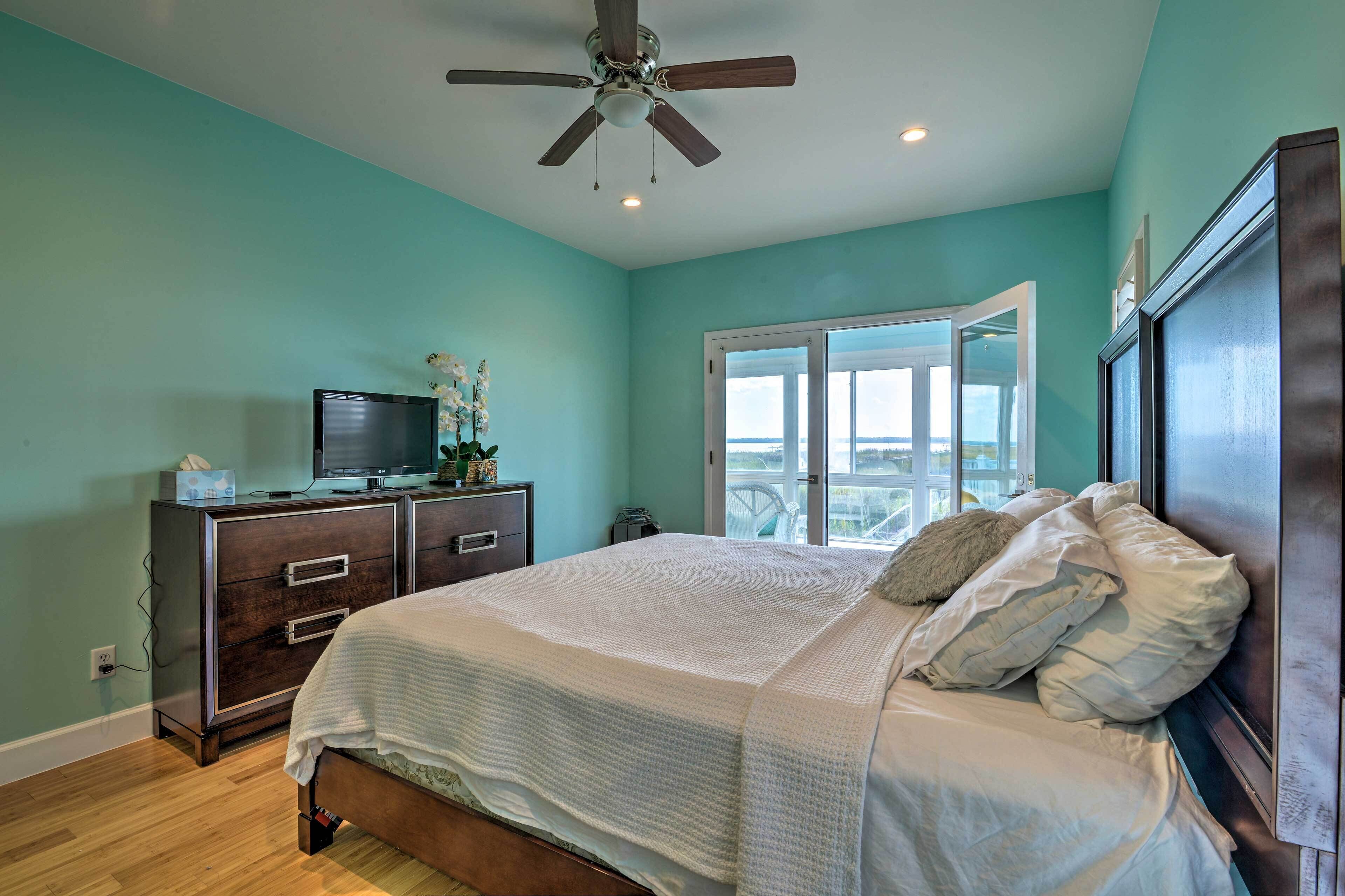 A bedroom with a bed, a dresser, a television, and a ceiling fan.
