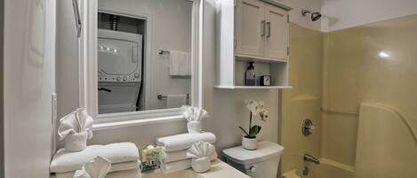 A bathroom with a sink, mirror, towel rack, toilet, and shower.