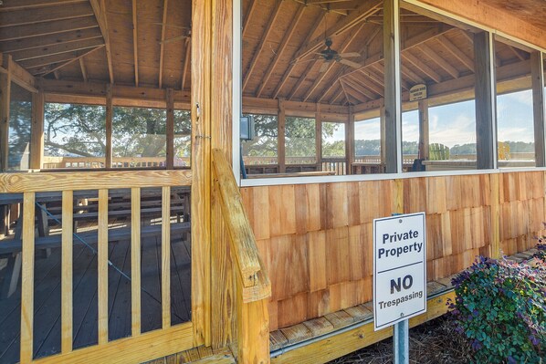 Un pavillon en bois, agrémenté d’un panneau indiquant « Propriété privée – entrée interdite », une terrasse en bois et une vue sur des arbres et un pont en arrière-plan.