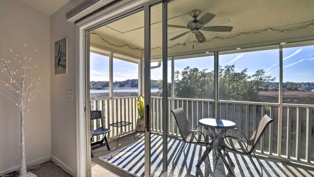 En balkon med glasdør, loftventilator og udsigt over landskabet.