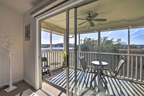 A balcony with a glass door, a ceiling fan, and a view of the landscape. - Little River Condo With Balcony & Pool Access! (Little River)