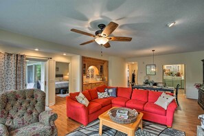 A living room with a red sectional sofa, a patterned armchair, and a wooden coffee table.