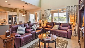 A spacious living room with leather sofas, a coffee table, and a kitchen in the background.