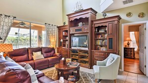 A spacious living room with leather sofas, a television, and a bookshelf.
