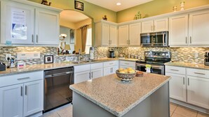 A modern kitchen with white cabinets, granite countertops, a microwave, stove, and a dishwasher.