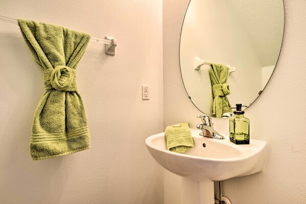 A bathroom with a white sink, a mirror, and a towel hanging on a towel rack.