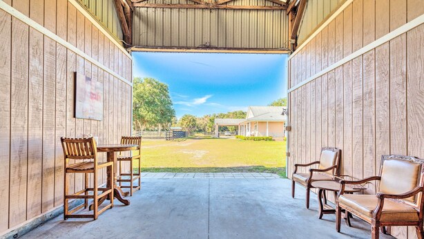 An open-sided barn with wooden walls and a concrete floor. Inside, there are wooden tables and chairs arranged for seating. - Lady Lake Studio - 7 Mi Lake Griffin State Park! (Lady Lake)