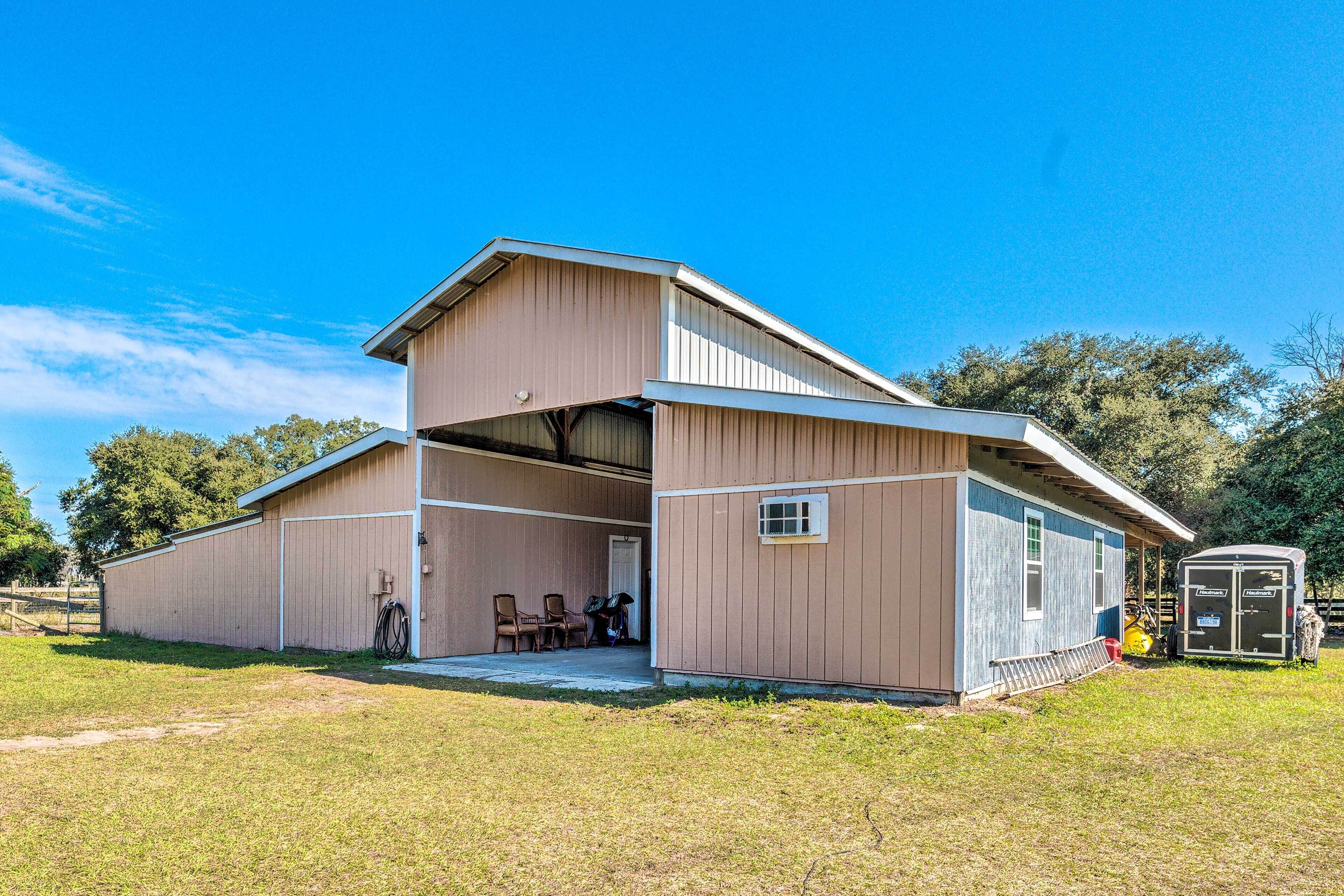A large, single-story barn with a covered porch and a small attached shed.