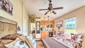 A bedroom with a bed, a ceiling fan, a view of the kitchen, and a window. - Lady Lake Studio - 7 Mi Lake Griffin State Park! (Lady Lake)