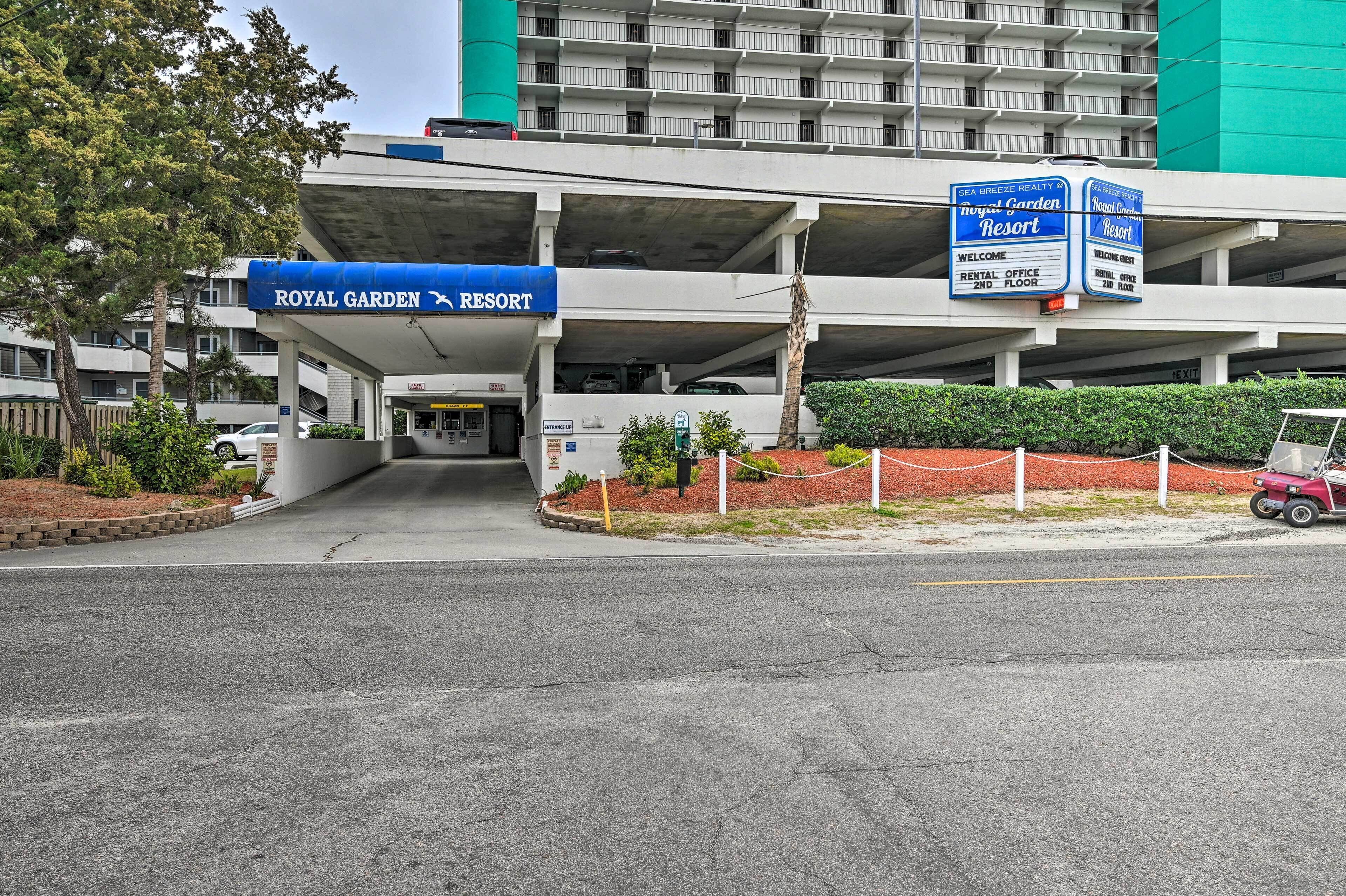 Ein Hotel Eingang mit einem Schild für Royal Garden Resort, einer Parkgarage und einem Verleih.
