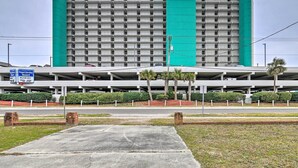 Un hotel con una llamativa decoración verde y blanca, varios pisos y un estacionamiento al fondo.