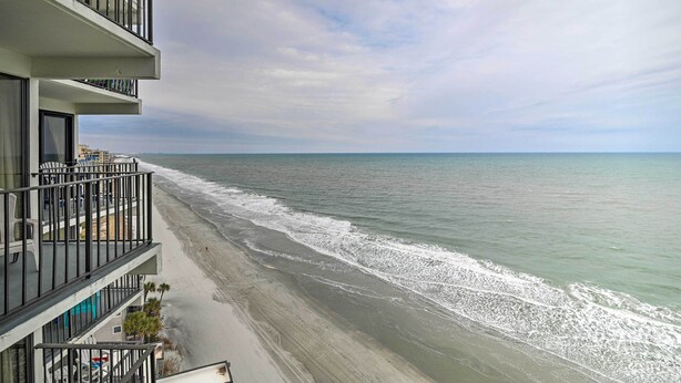 Un hotel frente a la playa con varios balcones con vistas al océano.